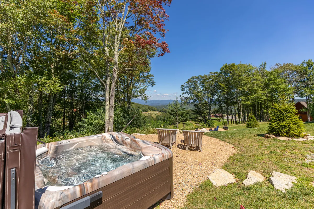 This image centers on a bubbling hot tub set against a backdrop of sweeping mountain vistas, with comfortable outdoor seating nearby. The tranquil ambiance is perfect for unwinding while soaking in the natural scenery, and the area is clearly designed for relaxation and socializing.