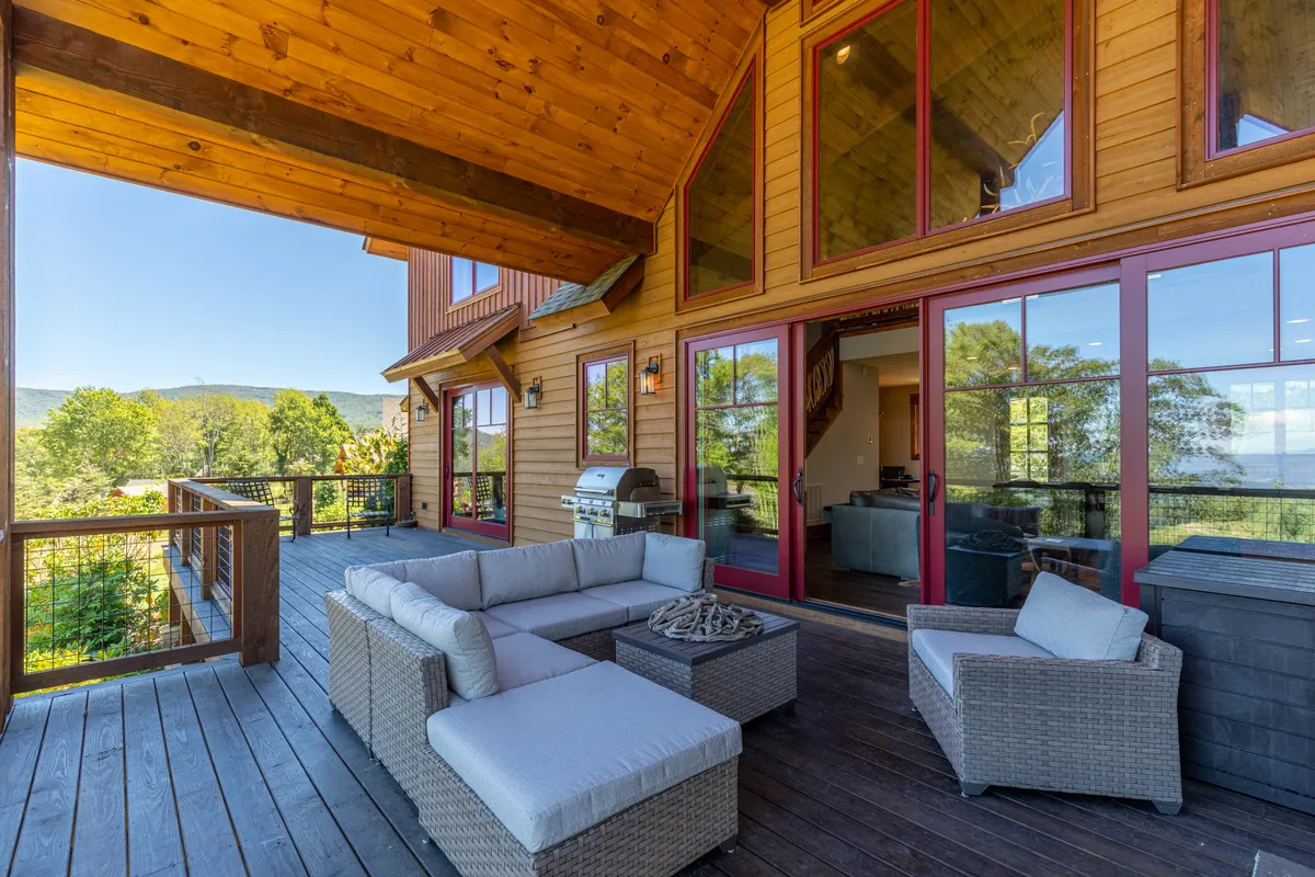 A comfortable outdoor seating area with large windows and stunning mountain views, designed for relaxation, entertaining guests, and barbecuing. The scene highlights a harmonious blend of luxury and nature.